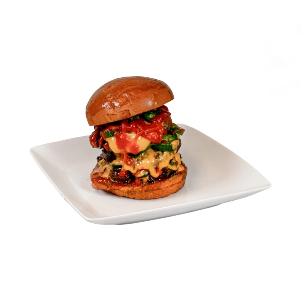 A double cheeseburger from Burger Xpress, topped with melted cheese, red sauce, and green peppers.